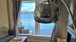 Une pièce avec une grande fenêtre, un canapé, une table et un lampadaire.