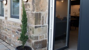 Un edificio de piedra con una puerta que da a una habitación con suelo de baldosas y felpudo.