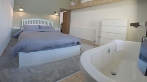 Un dormitorio con cama, una bañera grande y un radiador.