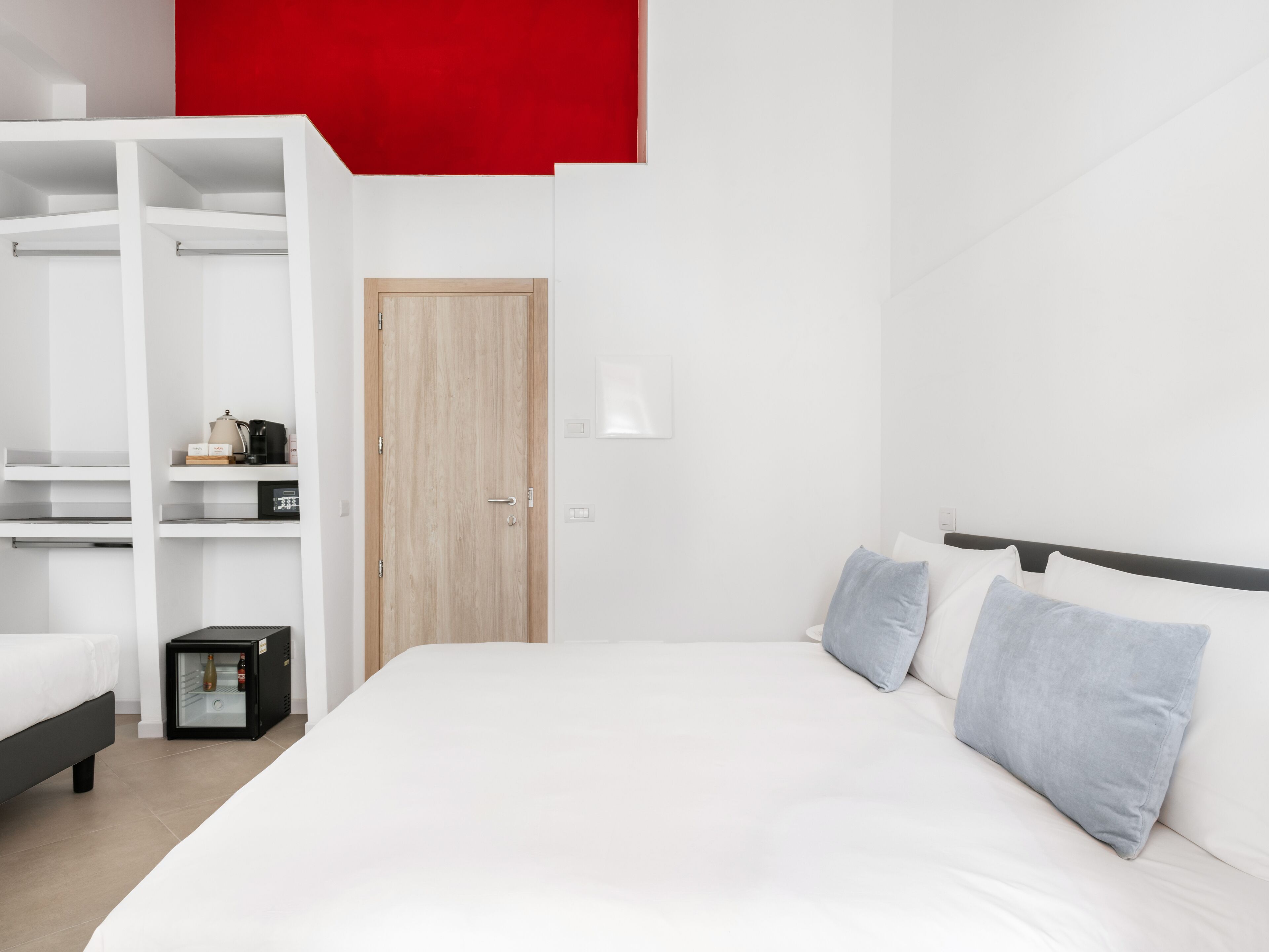 A modern bedroom with a large bed, a wardrobe, and a small bedside table.