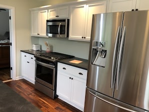 A kitchen with stainless steel appliances, white cabinets, and a wood floor.