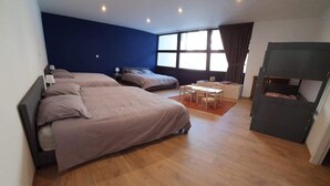 A bedroom with two beds, a small table, and a TV.