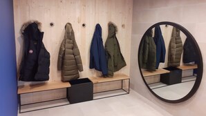 A coat storage area with multiple coats hanging on wooden shelves and a mirror on the wall.