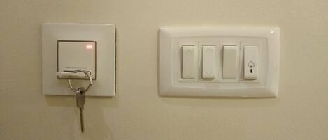 A wall-mounted electrical panel with a key lock and a separate switchboard with four switches and a light switch.