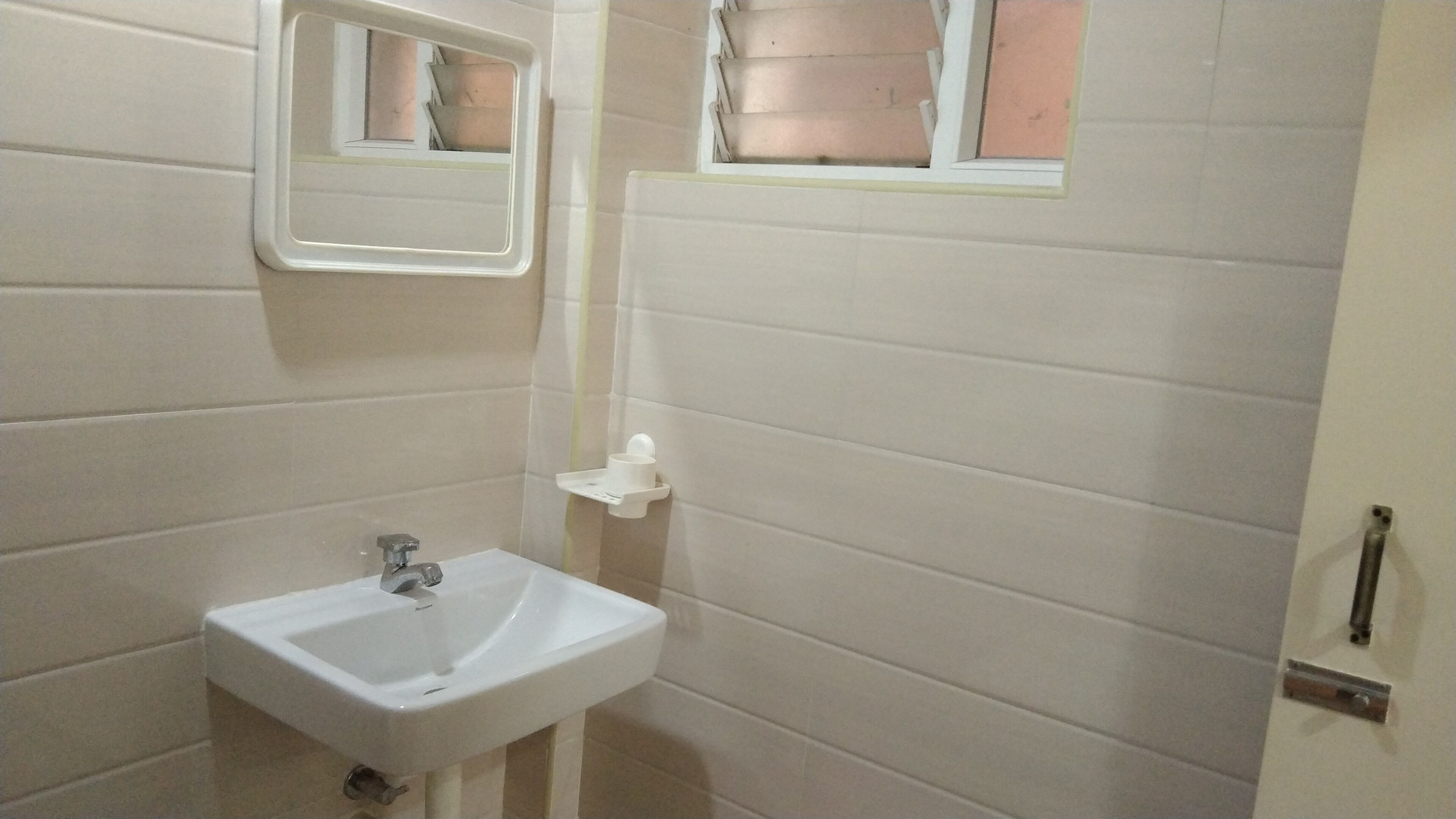 Un bagno con un lavandino bianco, uno specchio e una finestra.