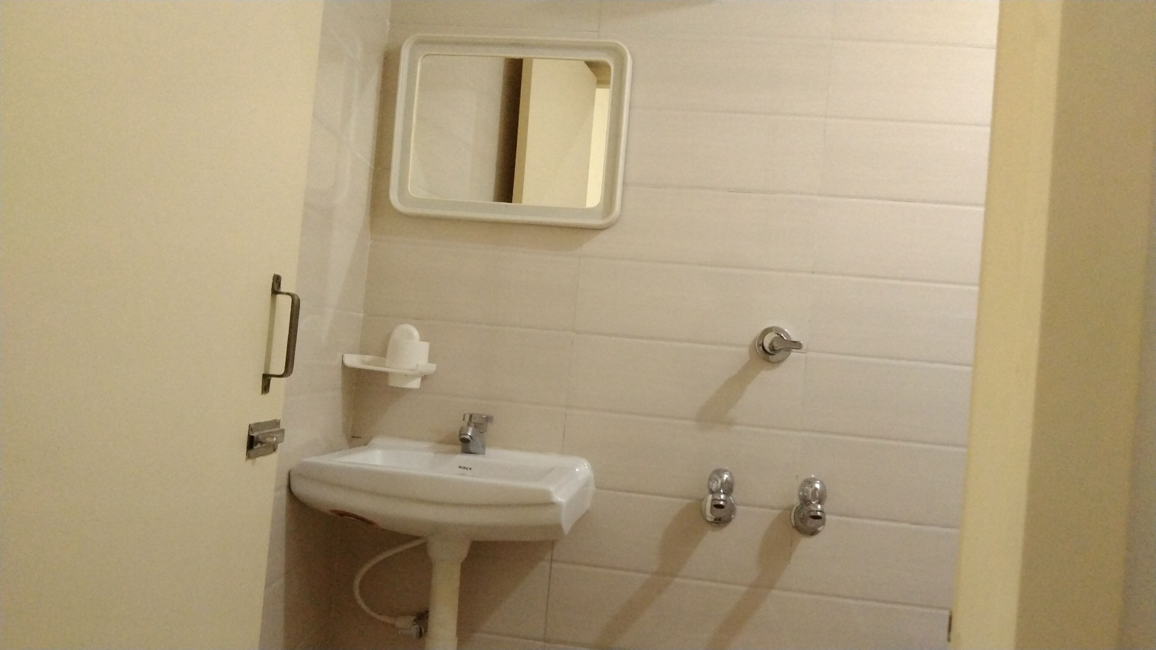 Un baño pequeño con un lavamanos blanco, un espejo y dos grifos.