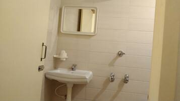 Un baño pequeño con un lavamanos blanco, un espejo y dos grifos.