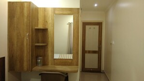 Quarto compacto com um guarda-roupa de madeira, uma pequena mesa de cabeceira e um espelho.