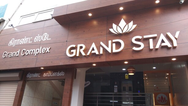 Placa de hotel com o nome 'Grand Stay' e um logotipo acima.