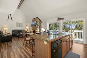 Un amplio espacio habitable con una isla de cocina, piso de madera y un ventanal con vistas a una terraza.