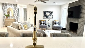 A modern kitchen with a stainless steel sink, a ceiling fan, and a fireplace.