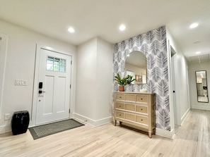 Welcoming foyer has stylish wallpaper and spot for keys and other items.