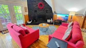 A living room with a stone fireplace, red sofas, a coffee table, and a television.