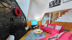 A modern living room with a stone fireplace, red sofa, and a television.