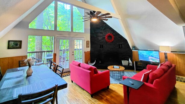 A spacious loft with high ceilings, large windows, a stone fireplace, and red furniture.