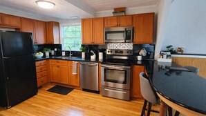 A modern kitchen with wooden cabinets, stainless steel appliances, and a black countertop.