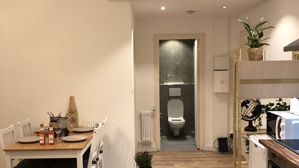 Une cuisine moderne avec un coin repas, un plancher en bois et une vue sur la salle de bain.