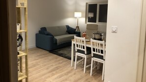 Un salon avec un canapé, une table à manger et des chaises, une lampe et une fenêtre.