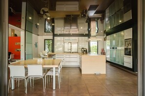 Una cocina moderna con armarios blancos, una isla central y un comedor con sillas blancas.