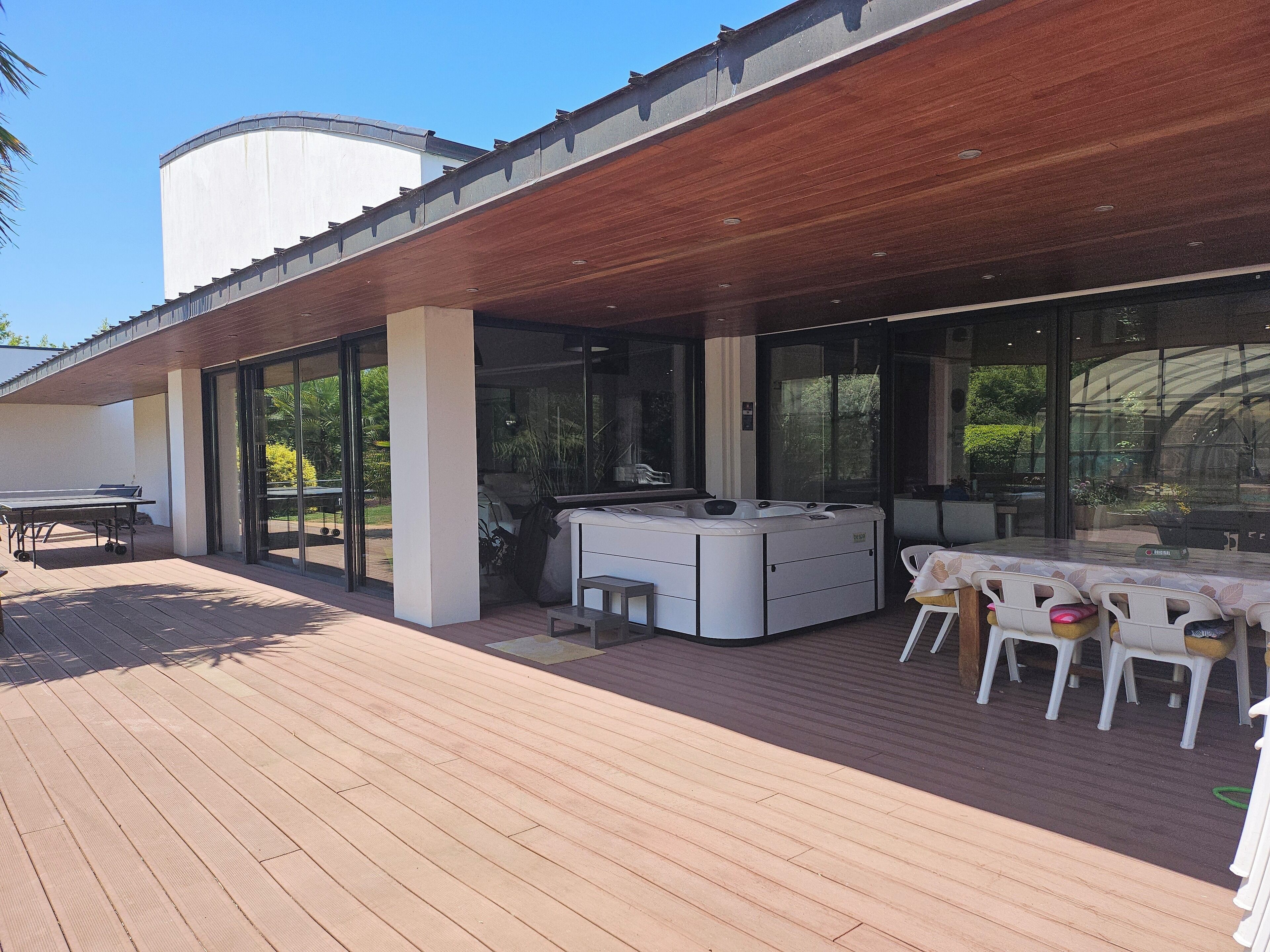 Eine Terrasse im Freien mit Whirlpool, Sitzgelegenheit und Tisch.