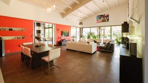 A spacious living area with a high ceiling, a dining area with a long table, and a seating area with sofas. - Spacious house with heated pool 7 minutes from the sea. (Les sables d olonne)