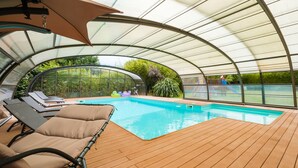 An indoor swimming pool with a wooden deck, lounge chairs, and a glass ceiling. - Spacious house with heated pool 7 minutes from the sea. (Les sables d olonne)