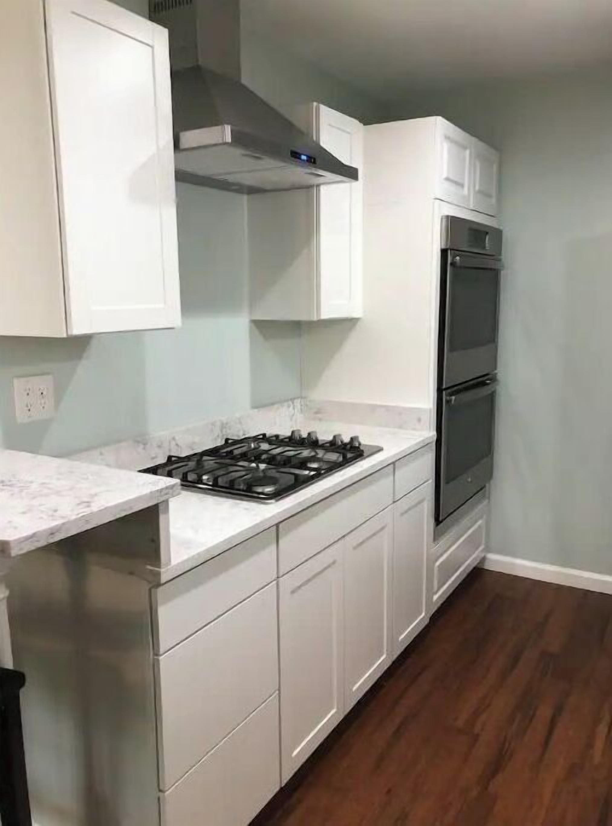 A kitchen with white cabinets, a gas stove, and a built-in oven.