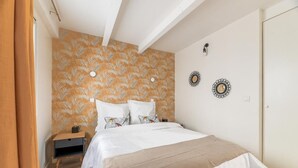 A bedroom with a bed, a nightstand, and a wall with decorative plates. - Villa Poncelet - Suite Coco mademoiselle, 2 Bdrs, Champs Elysées, A/C, Prime Loc (Paris-17E-Arrondissement)