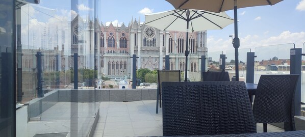 A balcony with wicker chairs and a table, overlooking a historic building with intricate architecture. - La Casa Mia Leon (León)