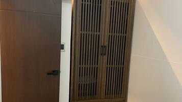 A bedroom with a bed, a wardrobe, and a television mounted on the wall.
