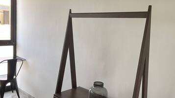 Una habitación con un escritorio y una silla de madera, un televisor montado en la pared y una ventana que proporciona luz natural.