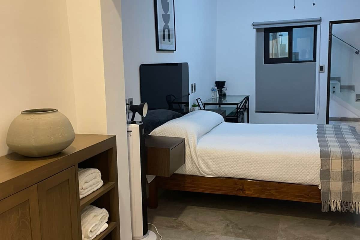 A bedroom with a bed, a bedside table, a lamp, a vase, and a wardrobe.