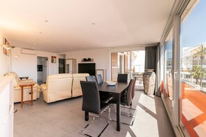 A modern living room with a dining area, a sofa, a coffee table, and a TV.