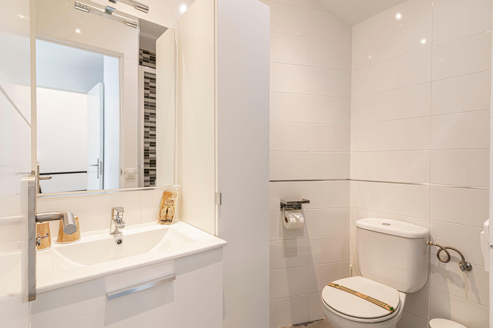 A modern bathroom with a white sink, a toilet, and a mirror.