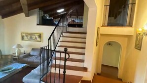 A staircase leading to an upper floor with a fireplace and a framed picture on the wall.