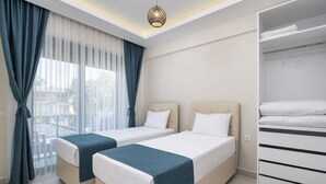 Una camera d'albergo con due letti, un armadio e un'ampia finestra con tende.