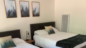 A room with two beds, each with a dark headboard and white bedding. There are three framed pictures on the wall above the beds. - Sierra Inn on the River (Kyburz)