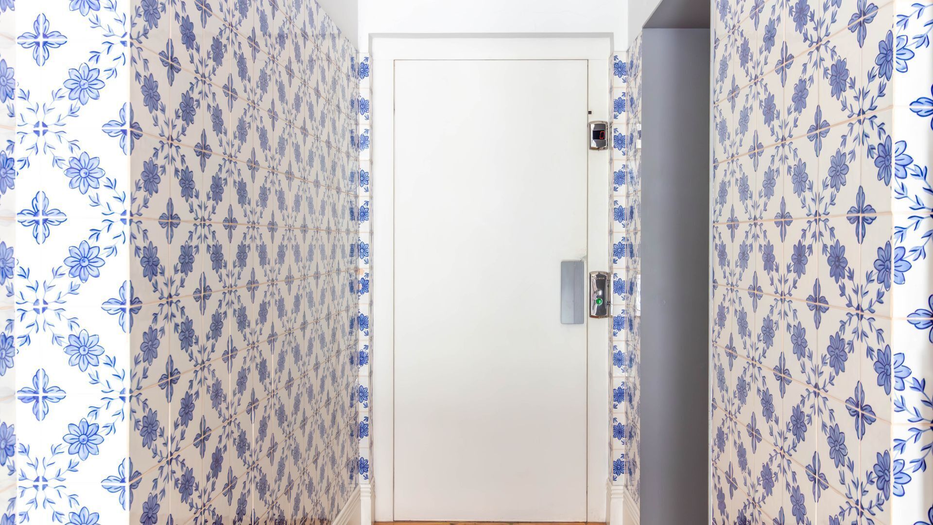 A door with a keyhole and a lock, flanked by patterned wallpaper.