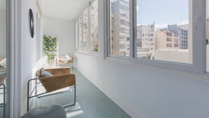 Ein Balkon mit Korbmöbeln, einem Blumentopf und Blick auf umliegende Gebäude.