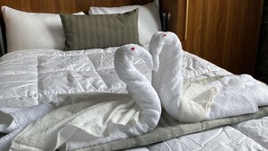 A hotel room with a neatly made bed, a wooden headboard, and a wooden door.