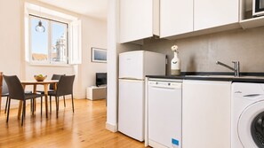 A compact kitchen with a dishwasher, a washing machine, and a dining area with a table and chairs.