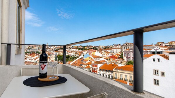 A balcony with a table, a bottle of wine, and a glass.