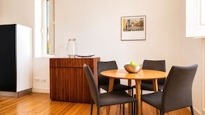 Ein Essbereich mit einem runden Holztisch, vier grauen Stühlen, einer Holzkommode und einem gerahmten Bild an der Wand.