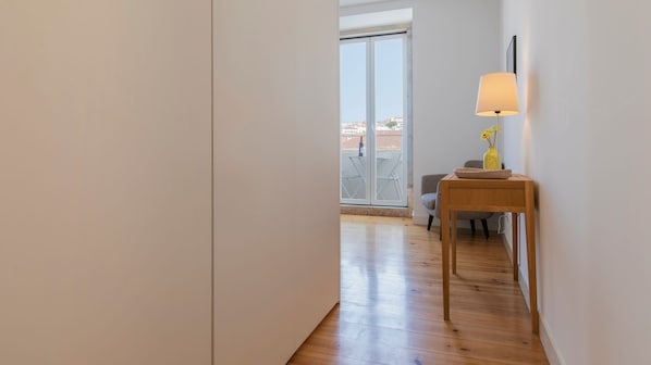 A hallway leading to a balcony with a view of buildings.