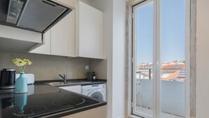 Une cuisine moderne équipée d’un lave-linge intégré, d’une machine à café et d’un vase rempli de fleurs posé sur le plan de travail.