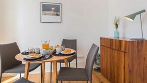 Un coin repas comprenant une table en bois, quatre chaises, un petit meuble et un tableau encadré accroché au mur.