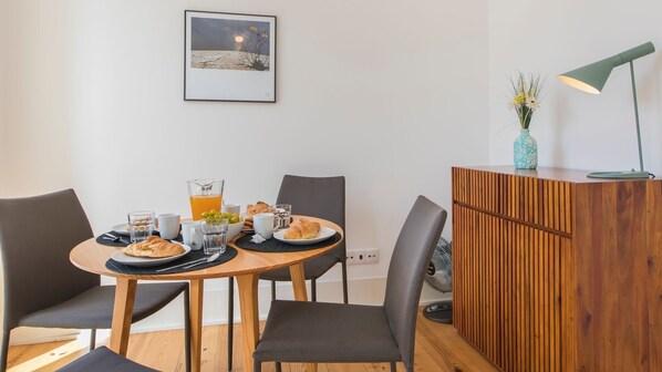 A dining area with a wooden table, four chairs, a small cabinet, and a framed picture on the wall.