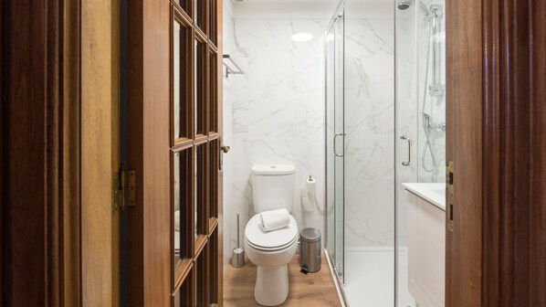 A modern bathroom with a toilet, a shower, and a glass-enclosed shower area. - Heritage Collection House w/ 4BR by LovelyStay (Porto)