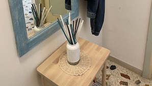 Un baño con espejo, tocador de madera, sombrero tejido y una chaqueta vaquera colgada en la pared.