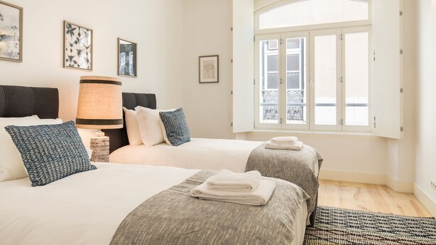 A hotel room with two beds, a large window, and artwork on the walls. - Hidden Oasis 2BDR Apartment by LovelyStay (Lisboa)
